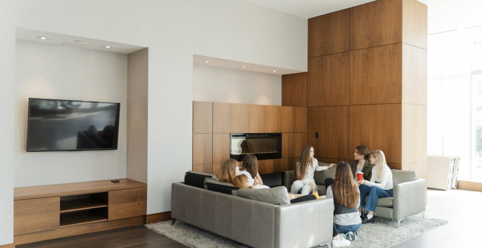 Group of young colleagues sitting at modern home, eating tasty food and talking with each other. People lifestyle concept